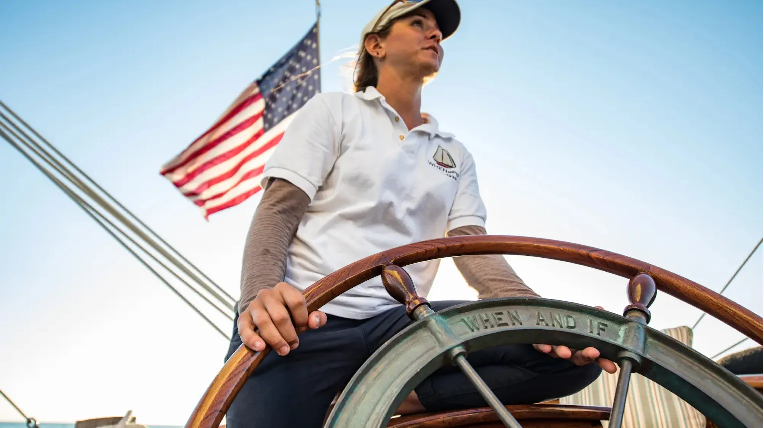A Sunset Sail Salem captain at the helm under the American flag